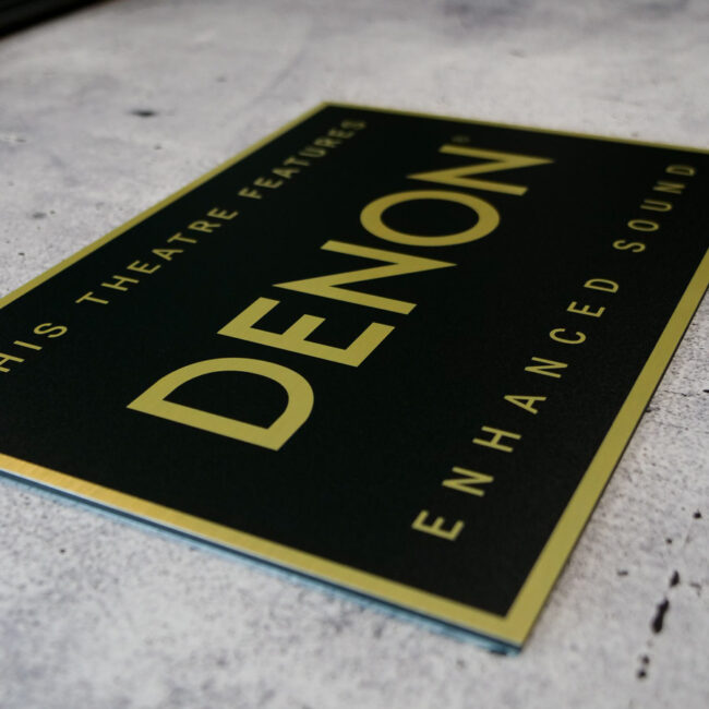 Schild in Schwarz-Gold mit dem Denon Logo