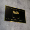 Schild in Schwarz-Gold mit dem NAD Logo